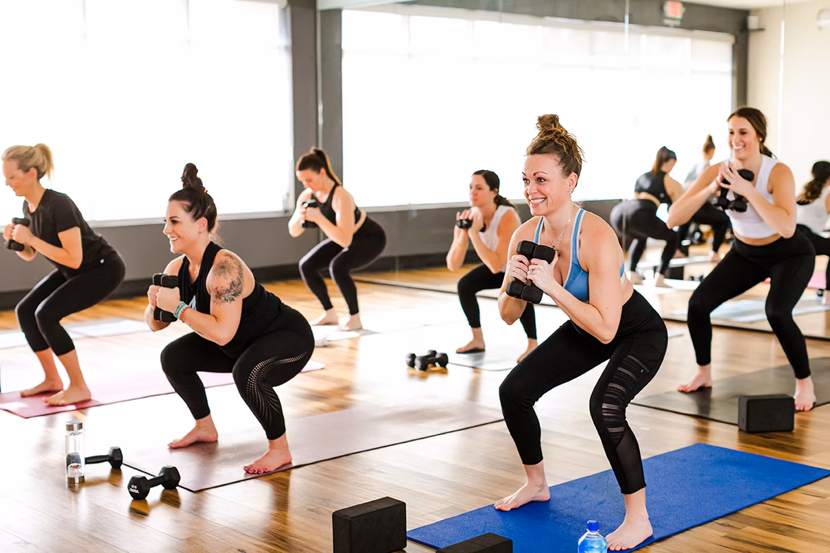 A Sculpt class mid-squat with dumbbells and big smiles